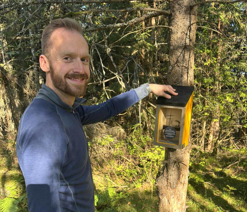 Mann og kasse med innhold på et tre.  - Klikk for stort bilde