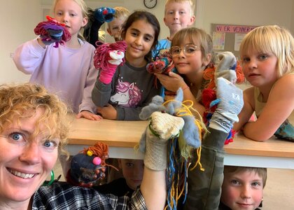 Kunstneren Shelli Lake og elever ved Fåset barneskole viser frem sine troll laget av sokker.  - Klikk for stort bilde